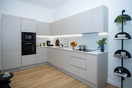 A modern kitchen with white cabinets and a wooden floor.