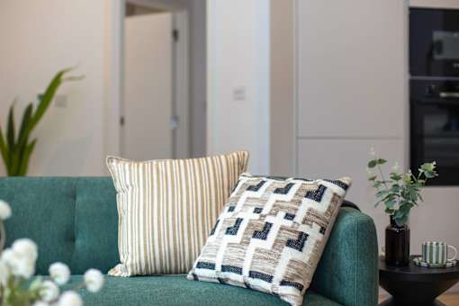 A green couch with two pillows on it.
