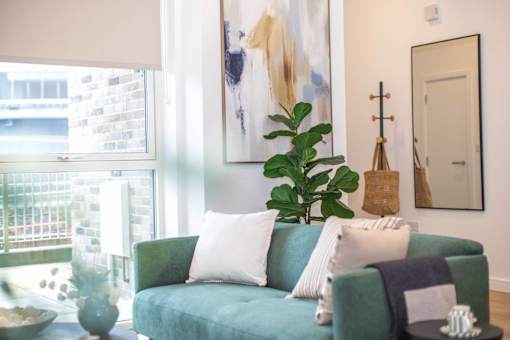 A living room with a green couch and a large painting on the wall.