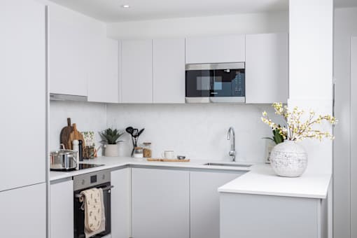A white kitchen with a sink, stove, and cabinets.