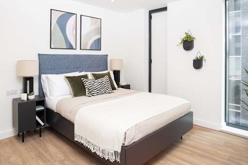 A bedroom with a bed, nightstands, and a window.