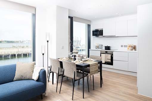 A modern kitchen with a dining table set for two.