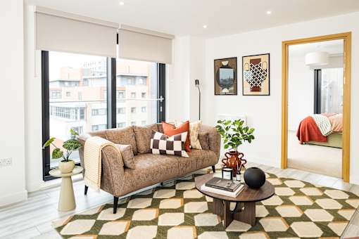 A living room with a brown couch and a checkered rug.