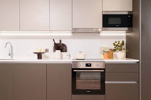 A modern kitchen with a black oven and white cabinets.