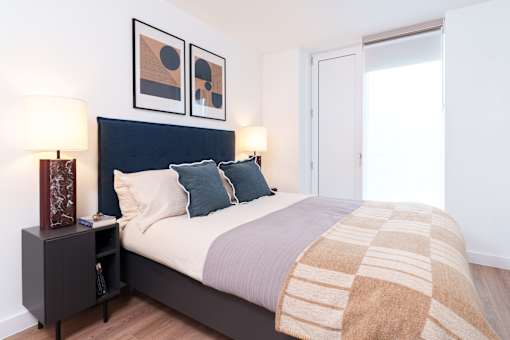 A bedroom with a bed, nightstand, and two framed pictures on the wall.