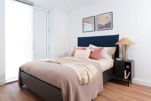 A bedroom with a bed, nightstand, and lamp.