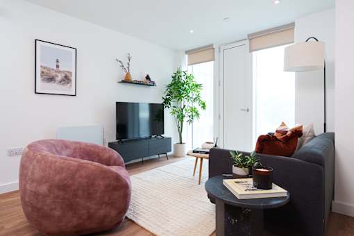 A living room with a grey couch, a red chair, a black coffee table, and a flat screen TV.