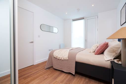 A bedroom with a bed, a mirror, and a lamp.
