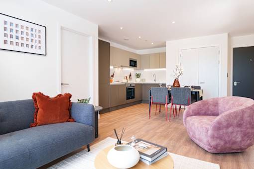 A living room with a blue couch and a pink chair.