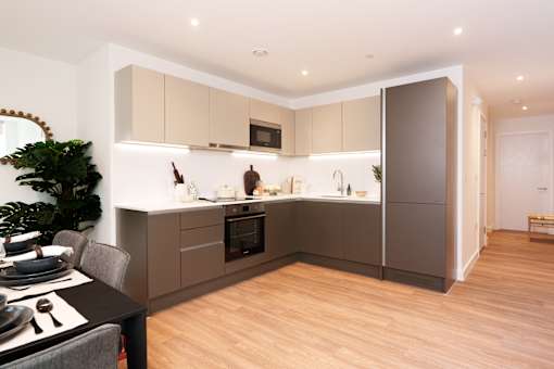 A modern kitchen with wooden floors and a dining table set for two.