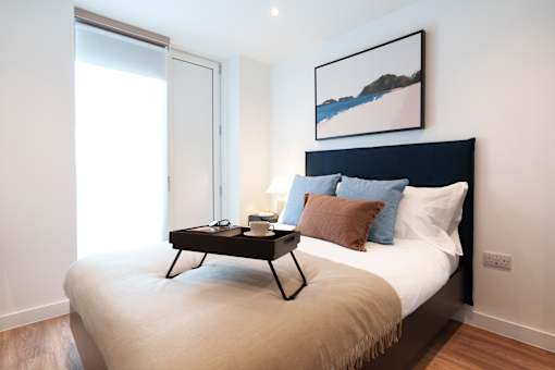 A bedroom with a bed, a nightstand, and a painting on the wall.