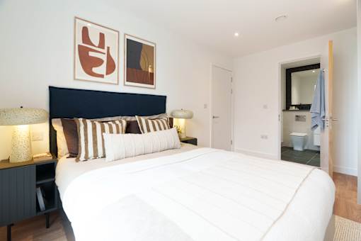 A bedroom with a large bed and two lamps on the side table.