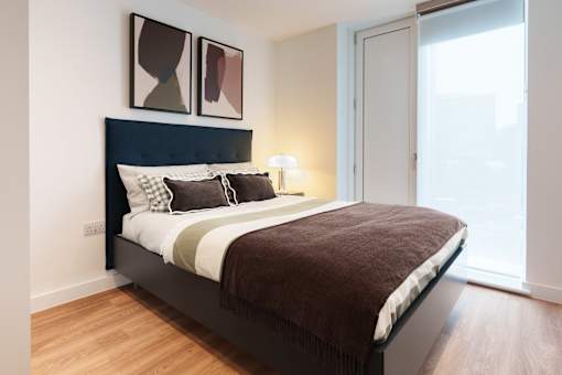 A bedroom with a large bed and two framed pictures on the wall.