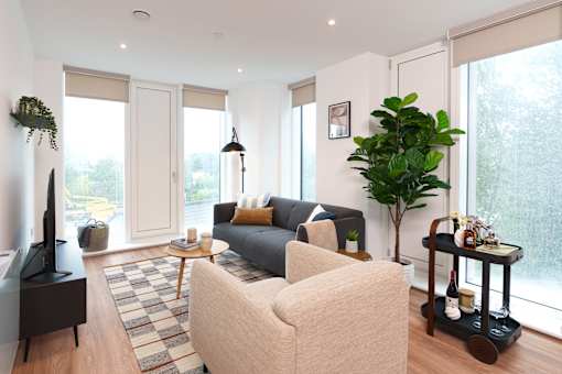 A living room with a grey couch, a white armchair, a wooden coffee table, and a black television.