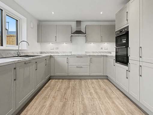 A kitchen with white cabinets and a wooden floor.at The Quarters Apartments, Dock Road