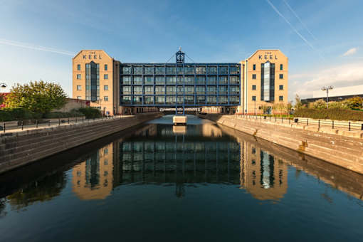 a canal with a boat in front of a large building at The Keel Apartments, Liverpool