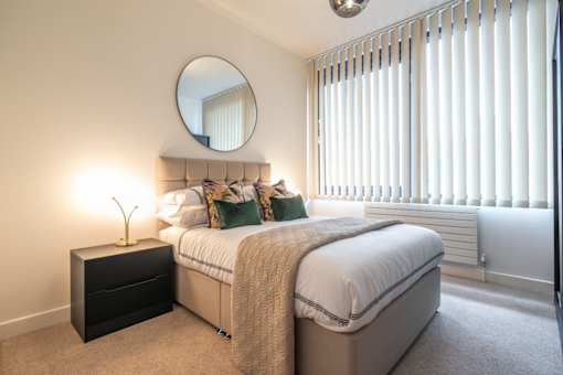 a white bedroom with a bed and a mirror at The Keel Apartments, Liverpool