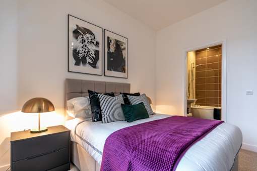 a bedroom with a large bed and a purple blanket at The Keel Apartments, Liverpool