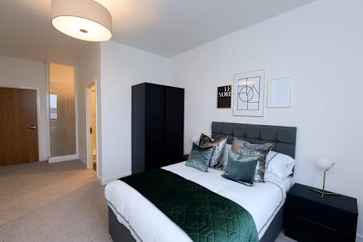 a bedroom with a bed and a black and white bedspread and pillows at The Keel Apartments, Liverpool