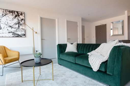 a living room with a green couch at Vox Apartments, Manchester