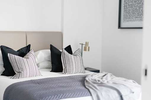 a bedroom with a bed with black and white pillows at Vox Apartments, Manchester