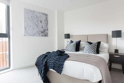 a bedroom with a bed and a large window at Vox Apartments, Manchester