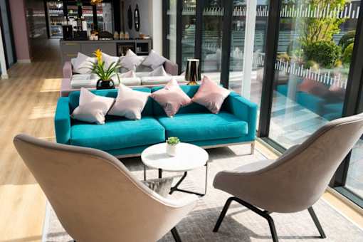 a living room with a blue couch and two chairs at The Trilogy Apartments, Manchester