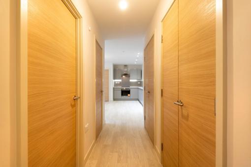a hallway with wooden doors and a kitchen in the background at The Trilogy Apartments, Manchester