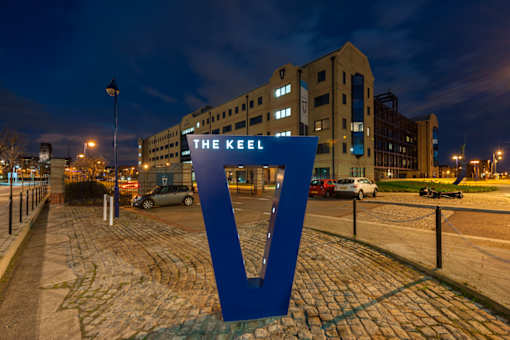 the keel signage in front of a building at night at The Keel Apartments, Liverpool