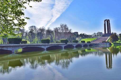 A bridge over a calm body of water with a monument in the background.