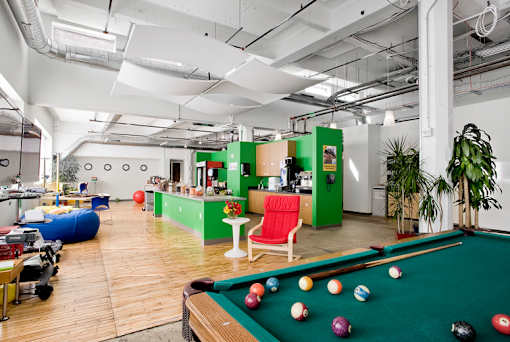 A pool table with balls set up for a game in a room with a green wall.