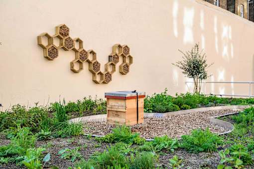 A beehive sits in front of a wall with a honeycomb pattern.