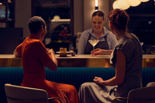 A woman in a red dress is sitting at a bar with a bartender.