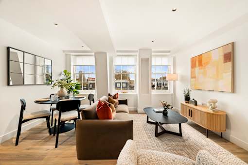 A living room with a brown couch, a black coffee table, and a large painting on the wall.