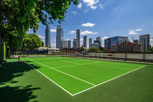 A tennis court with a city skyline in the background.