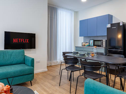 a living room with a table and chairs and a kitchen with blue cabinets
