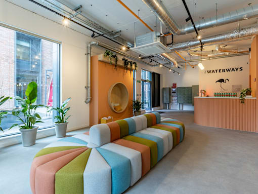a seating area with colorful cushions in front of a large window in an office