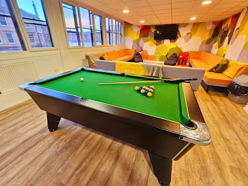 a game room with a pool table and orange couches