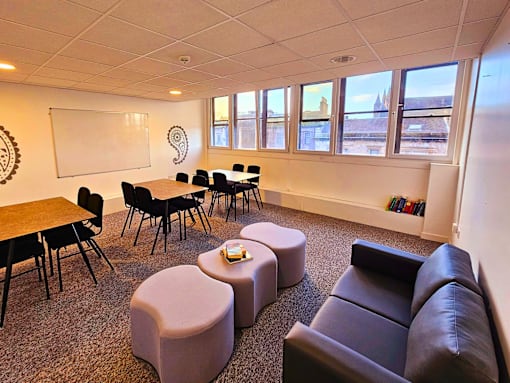 a living room with couches tables and chairs and a whiteboard