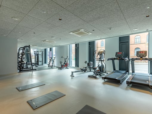 a gym with weights and other exercise equipment in a building with windows