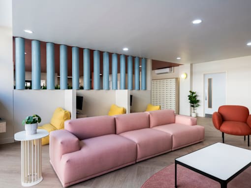a living room with a pink couch and yellow chairs