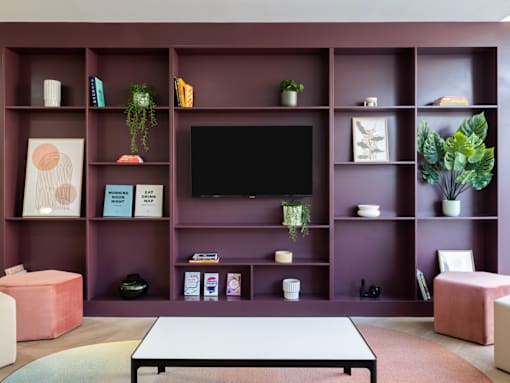 a living room with a purple bookshelf and a television