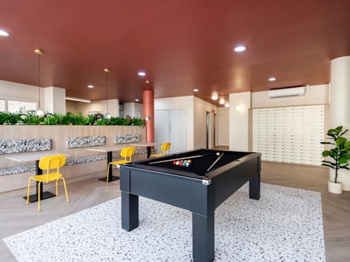 a pool table in a clubhouse with a bar and yellow chairs