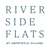 The image displays the text "River Side Flats at Woodlawn Village" in blue font on a green background.