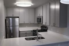 A kitchen with a stainless steel refrigerator and a black stove top oven.