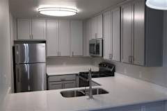 A kitchen with a stainless steel refrigerator and a black stove top oven.