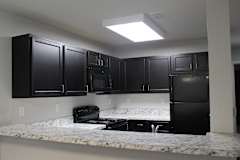 A kitchen with black cabinets and a marble countertop.