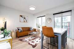 A living room with a brown couch, a white desk, and a rug.