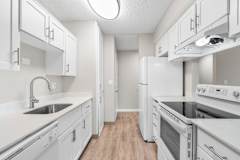 A white kitchen with a sink and stove.