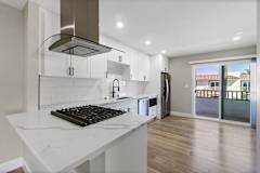 an open kitchen with white cabinets and a marble counter top at Ocean Breeze Terrace Apartment, Huntington Beach, 92648